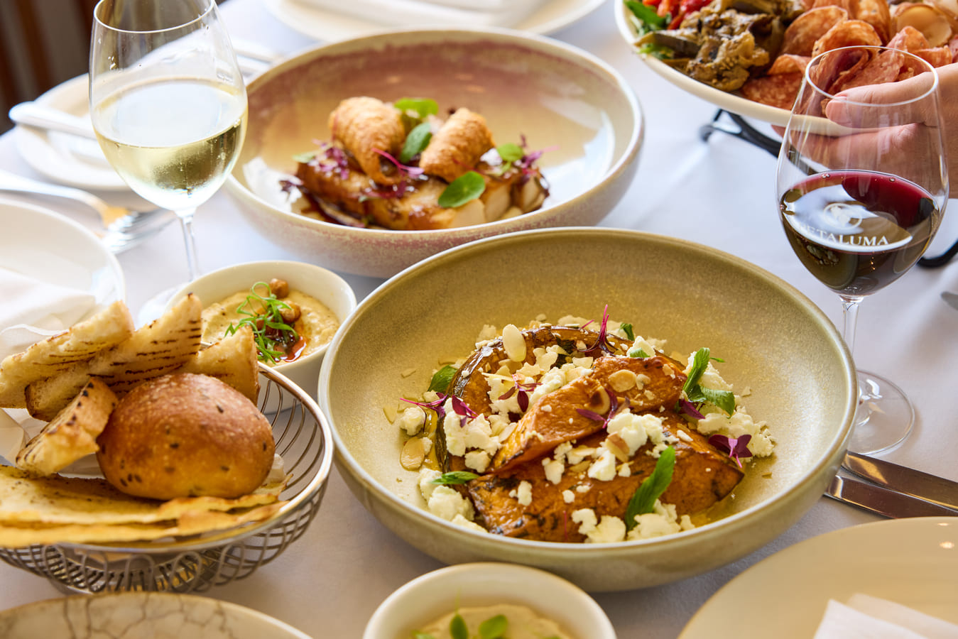 An array of savoury dishes on a table, with two wine glasses